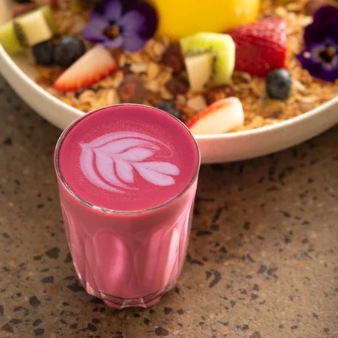 One glass of Beetroot Power Latte bright pink in colour made by Di Lorenzo Coffee sight a favourite breakfast plate