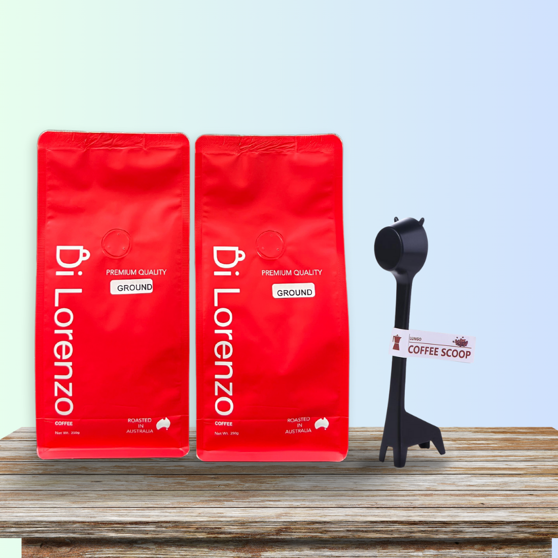 Two red bags of Di Lorenzo ground coffee on a wooden table, accompanied by a whimsical giraffe-shaped standing coffee scoop with a label, set against a serene blue gradient background.