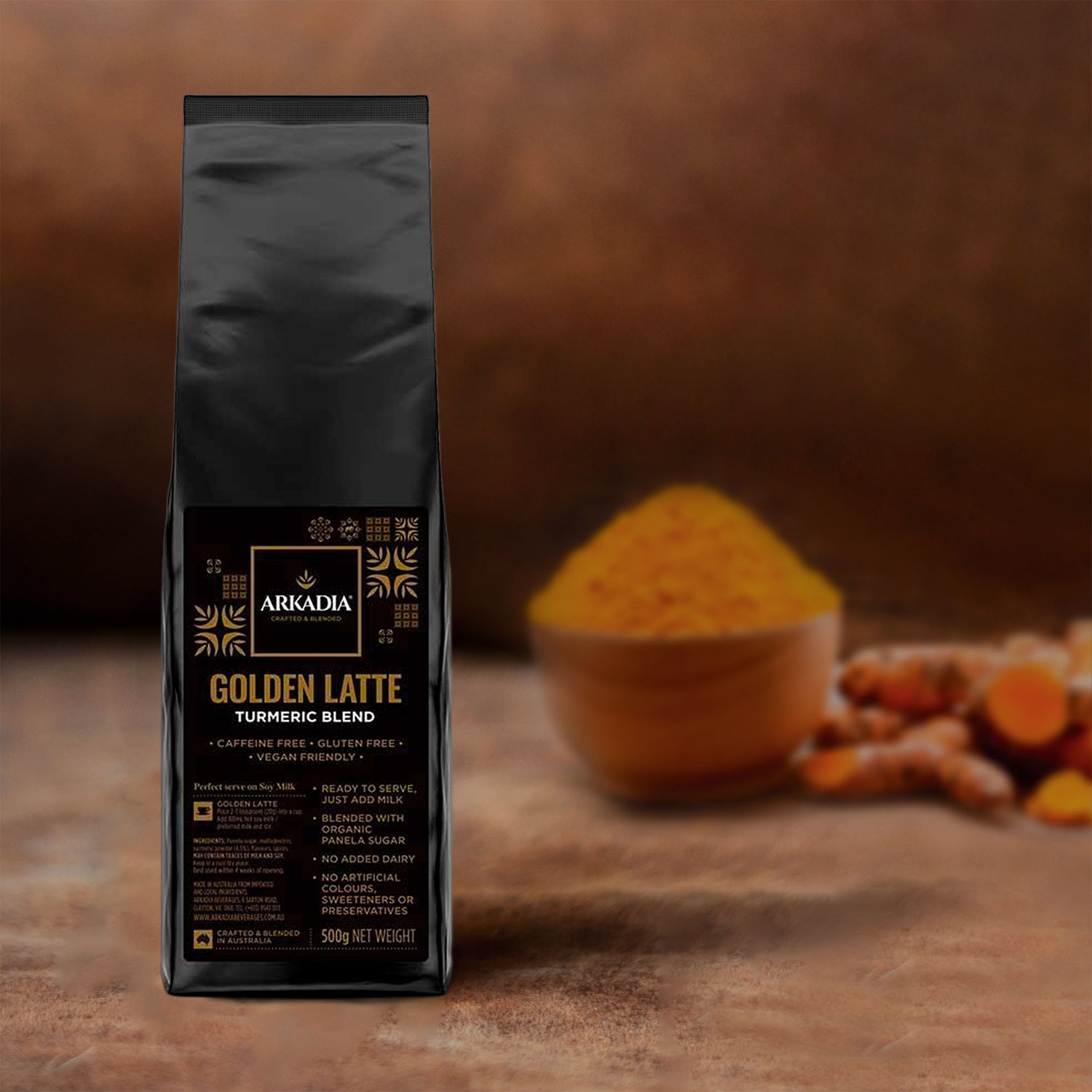 One black packet (next to a red bag coffee) with a golden label. Next the natural ingredients:  bowl of turmeric latte powder and turmeric fresh natural roots
